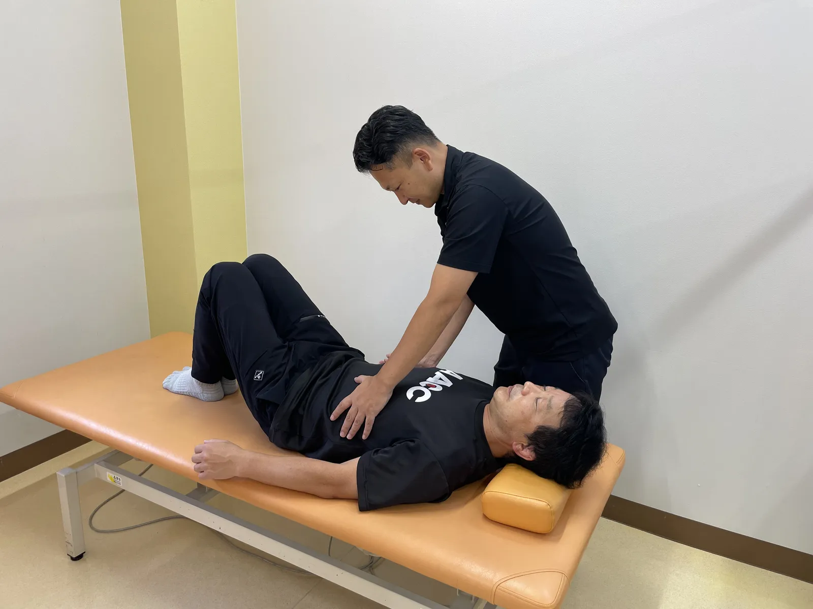 仰向けになったクライアントの呼吸を確認する蔦川さん